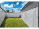 Enclosed back yard with white privacy fence and tropical landscaping and bright blue sky at 3906 Versailles Dr, Tampa, FL 33634
