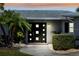 A modern front door with square windows, is surrounded by manicured landscaping at 3906 Versailles Dr, Tampa, FL 33634