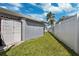 Narrow grass side yard with storage shed and vinyl privacy fence and view of palm trees at 3906 Versailles Dr, Tampa, FL 33634