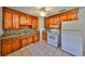 Functional kitchen featuring wooden cabinetry, tile backsplash, essential appliances, and tiled floor at 434 Pevetty Dr, Plant City, FL 33563