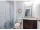 Cozy bathroom with patterned shower curtain, granite countertop and decorative mirror detail at 4764 Chatterton Way, Riverview, FL 33578