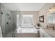 Elegant bathroom with marble-look tiling, a glass-enclosed shower, and a soaking tub at 4932 Wellbrook Dr, New Port Richey, FL 34653
