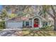 Inviting home exterior featuring a red front door, lush landscaping, and a two-car garage at 4932 Wellbrook Dr, New Port Richey, FL 34653