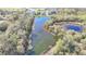 The aerial view shows the serene lake surrounded by lush trees and homes at 5016 Bella Armonia Cir, Wimauma, FL 33598