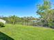 Large backyard featuring green grass, a black metal fence, and scenic views of a pond and wooded area at 5016 Bella Armonia Cir, Wimauma, FL 33598