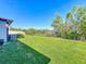 Expansive backyard featuring lush lawn, a fenced perimeter, and scenic views of surrounding trees and pond at 5016 Bella Armonia Cir, Wimauma, FL 33598
