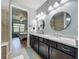 Elegant bathroom with a double vanity, granite countertop, and dual round mirrors at 5016 Bella Armonia Cir, Wimauma, FL 33598