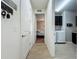 Hallway view leading to a bedroom and laundry room, showcasing neutral paint and wood-look tile flooring at 5016 Bella Armonia Cir, Wimauma, FL 33598
