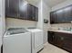 Laundry room with washer, dryer, dark cabinets and utility sink at 5016 Bella Armonia Cir, Wimauma, FL 33598