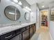 Well-lit bathroom boasting dual sinks with granite countertops and cabinetry, and a walk-in closet nearby at 5016 Bella Armonia Cir, Wimauma, FL 33598