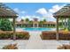 Community pool with pergola, palm trees, and lounge chairs at 5016 Bella Armonia Cir, Wimauma, FL 33598
