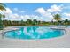 Community pool with sun loungers and palm trees against a beautiful sky at 5016 Bella Armonia Cir, Wimauma, FL 33598