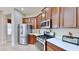 Well-lit kitchen features stainless steel appliances, white countertops, and wood cabinetry at 5709 Sea Turtle Pl, Apollo Beach, FL 33572