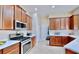 Well-equipped kitchen featuring wood cabinetry, stainless steel appliances and white countertops at 5709 Sea Turtle Pl, Apollo Beach, FL 33572