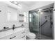 Modern bathroom with sleek white vanity, toilet, and glass-enclosed shower with black fixtures at 7208 Baltusrol Dr, New Port Richey, FL 34654