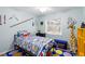 Brightly decorated bedroom with blue walls, unique decorations, and a window overlooking the backyard at 7208 Baltusrol Dr, New Port Richey, FL 34654
