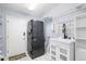 Convenient laundry room features stacked washer/dryer and utility sink with bright white tile flooring at 7208 Baltusrol Dr, New Port Richey, FL 34654