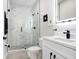 Well-lit bathroom featuring a glass-enclosed shower, vanity with black hardware, and white marble accents at 7403 Edgemere Rd, Tampa, FL 33625