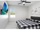 Bright bedroom with a plaid bedspread, modern ceiling fan, and decorative wall art at 7403 Edgemere Rd, Tampa, FL 33625