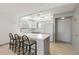 Open kitchen with bar seating, white appliances, white cabinetry, and gray lower cabinets at 7910 Sun Island S Dr # 302, South Pasadena, FL 33707