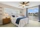 Bright bedroom featuring a ceiling fan, a cozy bed and a sliding glass door to the balcony with serene water views at 995 Eden Isle Ne Dr, St Petersburg, FL 33704