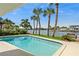 Backyard pool view featuring a waterfront view and swaying palm trees, perfect for relaxation at 995 Eden Isle Ne Dr, St Petersburg, FL 33704
