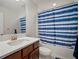 Well-lit bathroom features a single sink vanity with white countertop and tub with a blue and white shower curtain at 13103 Wildflower Meadow Dr, Riverview, FL 33579