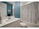 Stylish bathroom with a blue accent wall, floral shower curtain, and modern vanity at 13103 Wildflower Meadow Dr, Riverview, FL 33579