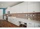 Bright kitchen with white cabinets, decorative backsplash, stainless steel appliances and a work station at 13103 Wildflower Meadow Dr, Riverview, FL 33579