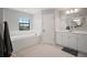 A well-lit main bathroom featuring a soaking tub, white cabinetry, and a large mirror reflecting the spacious layout at 13103 Wildflower Meadow Dr, Riverview, FL 33579