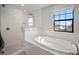 A modern main bathroom featuring a glass shower, a soaking tub, and a large window providing natural light at 13103 Wildflower Meadow Dr, Riverview, FL 33579