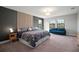 A spacious main bedroom featuring a decorative headboard and a comfortable blue sofa near bright windows at 13103 Wildflower Meadow Dr, Riverview, FL 33579