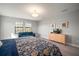 A bright main bedroom featuring a blue sofa, a stylish dresser, and views of the outside through large windows at 13103 Wildflower Meadow Dr, Riverview, FL 33579