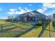 Large backyard with a screened-in pool and patio area surrounded by lush landscaping and a secure black metal fence at 14522 Woodland Spur Dr, Lithia, FL 33547