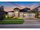 Beautiful home exterior with stone accents, manicured lawn, and three-car garage at dusk at 14522 Woodland Spur Dr, Lithia, FL 33547