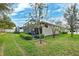 Expansive backyard with a screened-in patio, green grass, and mature trees at 1467 Twin Villas Way, Dunedin, FL 34698