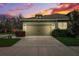 Charming single-story home featuring a two-car garage during a colorful sunset at 1467 Twin Villas Way, Dunedin, FL 34698