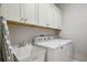 Bright laundry room with white cabinets, utility sink, and modern washer and dryer at 1467 Twin Villas Way, Dunedin, FL 34698