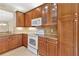 Kitchen with wood cabinets, granite counters, and white appliances, including range and microwave at 16232 Amethyst Key Dr, Wimauma, FL 33598