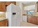 Close-up of the kitchen featuring granite counters, wood cabinets, and a modern refrigerator at 16232 Amethyst Key Dr, Wimauma, FL 33598
