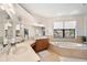 Bright main bathroom featuring dual sinks, cabinetry, a large soaking tub, and views of the water at 3598 10Th Ne St, St Petersburg, FL 33704