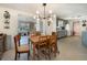 Bright dining room with a modern light fixture, wood table, and views into the kitchen and sunroom at 375 Magnolia Rd, Venice, FL 34293