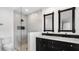 Renovated bathroom featuring a double vanity with black cabinets and a walk-in shower with marble tiling at 4358 Outrigger Ln, Tampa, FL 33615
