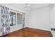 Bedroom featuring hardwood floors, a ceiling fan, and a window with blue patterned curtains at 4358 Outrigger Ln, Tampa, FL 33615