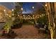 A charming backyard patio with a brick floor, string lights, garden, and multiple seating arrangements at dusk at 5024 W Homer Ave, Tampa, FL 33629