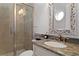 Bathroom featuring granite countertops, decorative mirrors, and a glass enclosed shower at 5024 W Homer Ave, Tampa, FL 33629