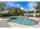 A backyard pool and jacuzzi with stone pavers, lounge seating, lush landscaping and a manicured garden at 5024 W Homer Ave, Tampa, FL 33629