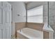 Elegant soaking tub in a well-lit bathroom, featuring white tiling and a window for natural light at 6308 Bridgevista Dr, Lithia, FL 33547
