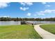 Scenic walking path leading to a dock on a peaceful lake under a blue sky with fluffy clouds at 6308 Bridgevista Dr, Lithia, FL 33547