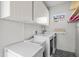 Functional laundry room with a washing machine, sink, storage cabinets, and patterned flooring at 701 S Edison Ave, Tampa, FL 33606